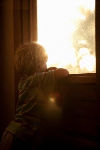 Young boy looking through window